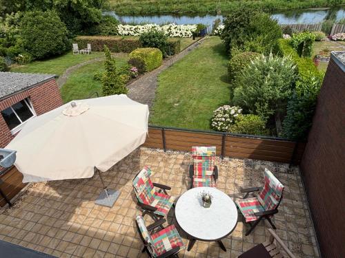 a patio with a table and chairs and an umbrella at Ferienhaus an der Niers in Weeze