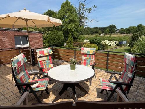 a patio with a table and chairs with an umbrella at Ferienhaus an der Niers in Weeze