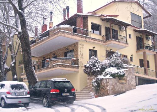 two cars parked in front of a house in the snow at Nostos Hotel in Kato Loutraki