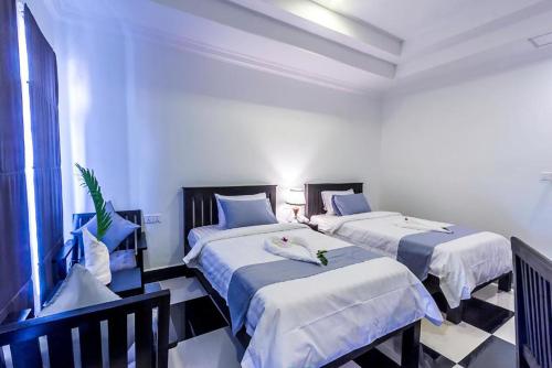 two beds in a room with white walls at Rithy Rine Angkor Residence in Siem Reap
