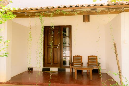 a room with two chairs and a table and a door at Eco Hotel Black & White - Anuradhapura in Mihintale