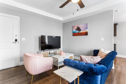 a living room with a blue couch and two pink chairs at Your Cozy One Bedroom Detriot in Detroit
