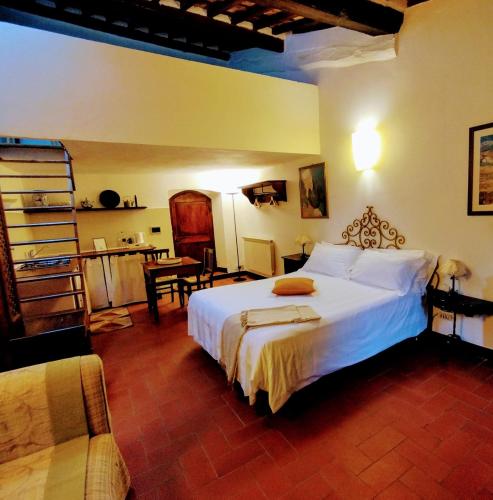 a bedroom with a white bed and a kitchen at L'orto Delle Terme in Bagno Vignoni