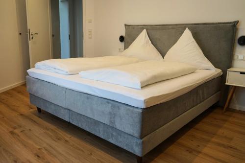 Una cama con sábanas blancas y almohadas. en Hain Estate Appartements, en Piesport