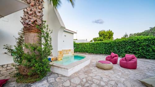 a swimming pool with pink furniture next to a tree at Villa Giglio with Garden and Mini Pool by Rentbeat in Rosa Marina