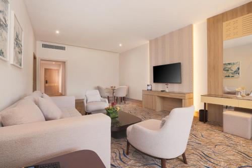 a living room with white furniture and a flat screen tv at Helnan Antoniades Palace Hotel in Alexandria