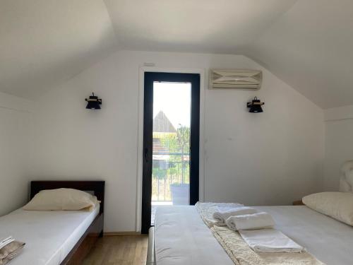 zwei Betten in einem weißen Zimmer mit Fenster in der Unterkunft Vikendica Dunja in Loznica