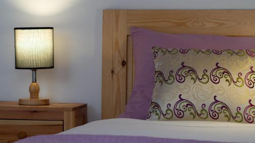 a bed with a purple pillow and a lamp on a night stand at Riad Al Manara in Essaouira