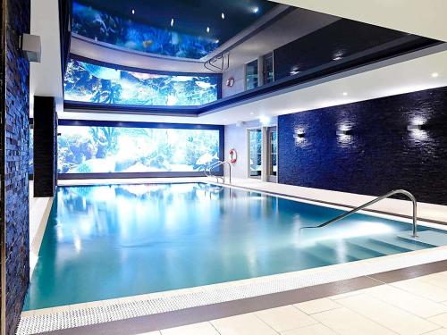 a swimming pool in a building with a large aquarium at Novotel London Brentford in Brentford