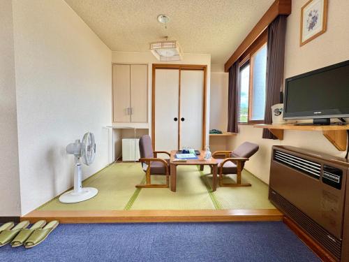 a living room with a table and chairs and a television at Hotel Sol at Lake Toya in Lake Toya