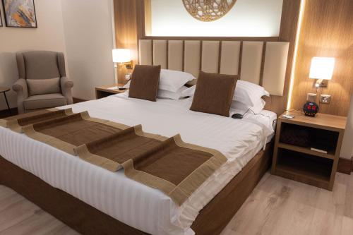 a bedroom with a large bed and a chair at Sakura City Hotel in Al Baha