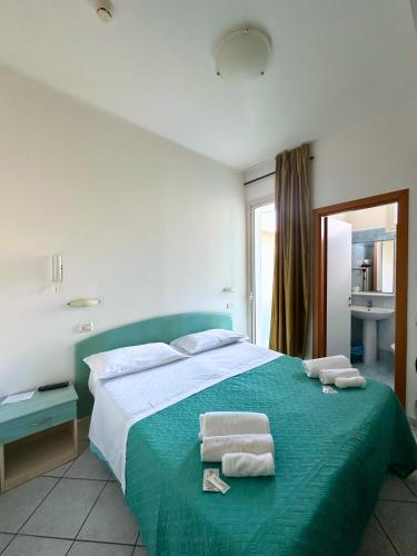 a bedroom with a green bed with towels on it at Hotel Ginevra e Residence in Cattolica