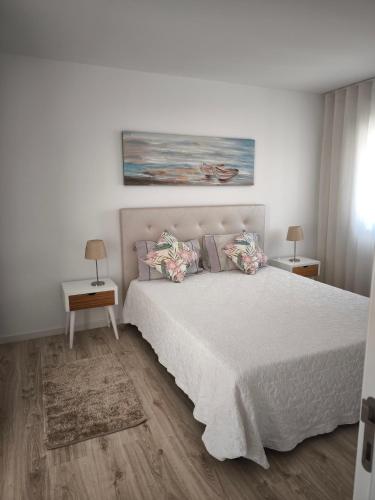 a bedroom with a white bed with two tables and two lamps at Gina House in Nazaré