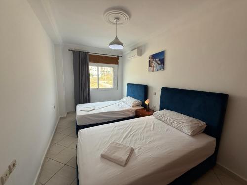 two twin beds in a room with a window at Home Together Family in Tetouan