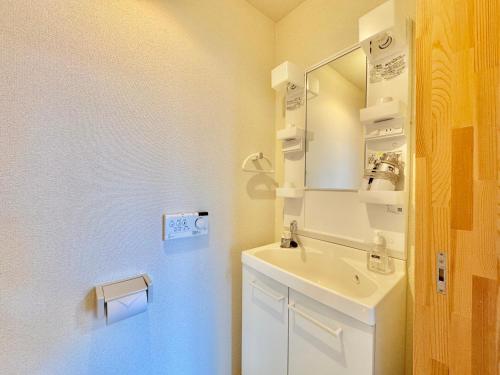 a white bathroom with a sink and a mirror at Hotel Sol at Lake Toya in Lake Toya