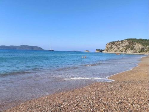 a beach with people swimming in the water at Villa in Finikounta near Sandy Beach in Finikounta