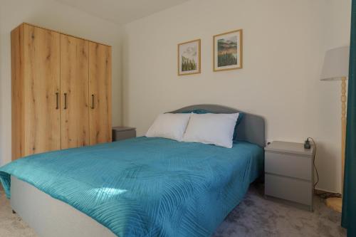 a bedroom with a blue bed with a wooden cabinet at MonteHygge apartments in Tivat