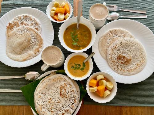 a table with plates of food and bowls of soup at Tattwamasi Annex with Breakfast and Yoga in Varkala