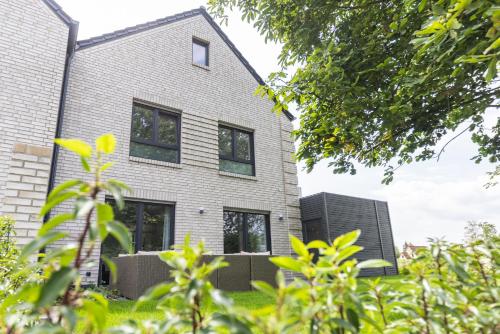 a house with black windows and green vegetation at Das Strandhaus 2, mit Garten, 250 Meter zum See in Lembruch