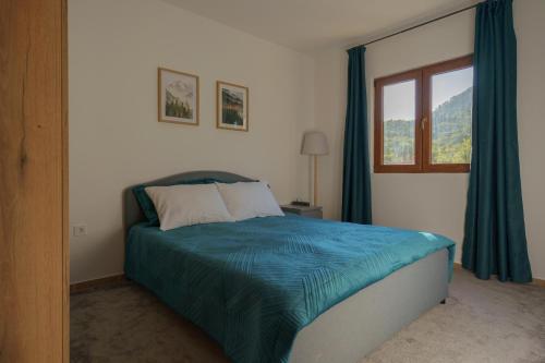 a bedroom with a bed with blue sheets and a window at MonteHygge apartments in Tivat