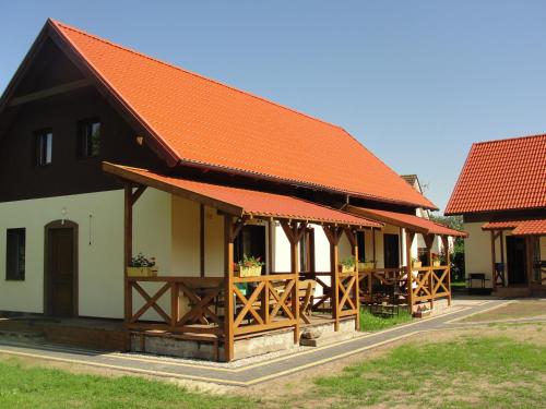a building with an orange roof and wooden tables at Pokoje i domki Saraceńska Chata in Stegna