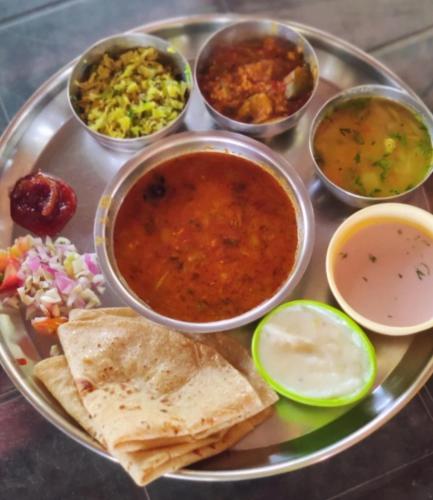 a plate of food with bowls of soup and other foods at Samant Beach Resort in Malvan