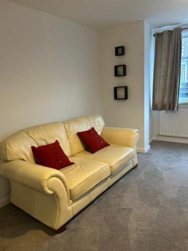 a yellow couch with two red pillows in a living room at Contractor and Family Cozy Home Sleeps 7 Free Parking in Grimsby