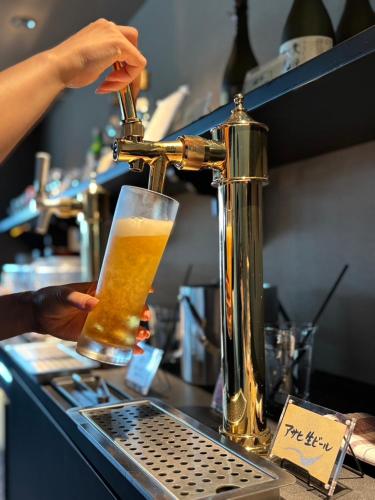 a person is preparing a glass of beer at a bar at hotel nansui in Kochi