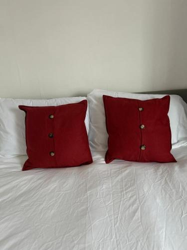 two red pillows sitting on top of a white bed at Contractor and Family Cozy Home Sleeps 7 Free Parking in Grimsby