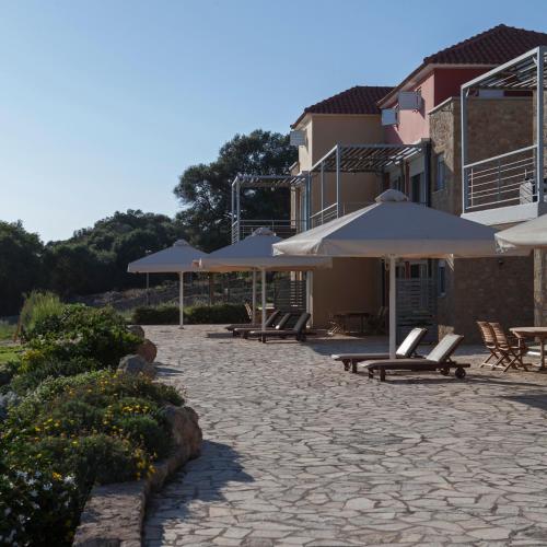 a patio with umbrellas and lounge chairs and tables at Dialiskari Villas in Marathopolis