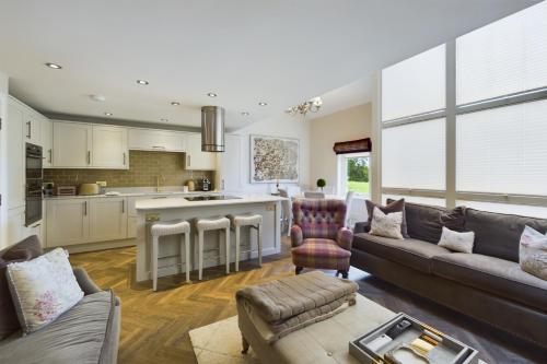 a living room with a couch and a kitchen at Beech Meadow-Home from Home Luxury Holiday Cottage in Kirkby Lonsdale