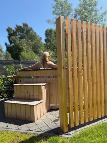 a woman sitting on a bench behind a wooden fence at Widać Wydmy in Łeba