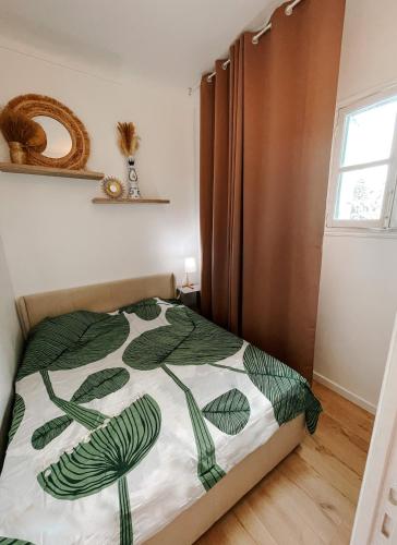 a bedroom with a bed with a green and white comforter at Quiet and bright apartment with separate bedroom in Nice