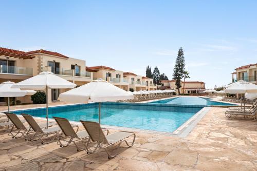 a swimming pool with lounge chairs and umbrellas at Freij Hotel & Resort in Ayia Napa