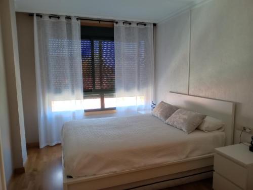 Un dormitorio con una cama blanca y una ventana. en apartamento vilariño, en Cangas de Morrazo