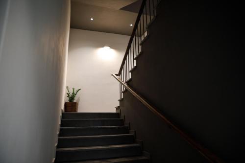 a stairway with a light on the wall and a plant at Stitch&Stone Suites in Gjirokastër