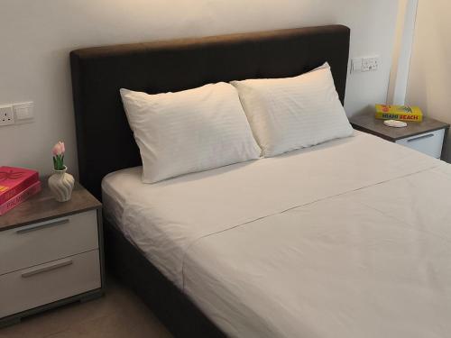 a bed with white sheets and a black headboard at Joyscape beachfront residence in Larnaca
