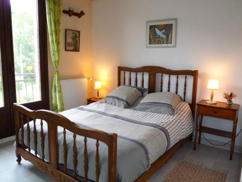 - une chambre avec un grand lit en bois et 2 lampes dans l'établissement Gîte de Lamourade, à Saint-Ferriol