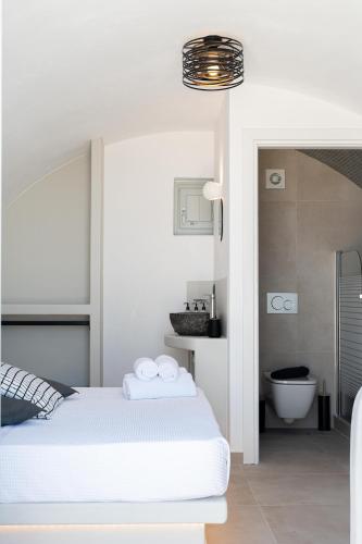a white bedroom with a bed and a bathroom at AetherOia Suites in Oia