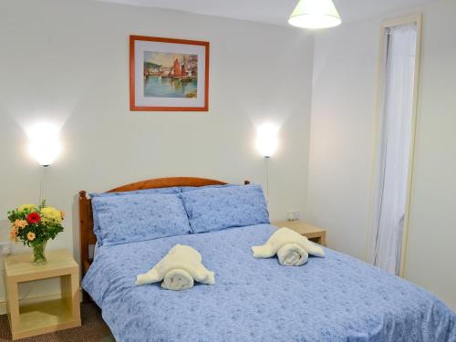 a bedroom with a blue bed with towels on it at The Cobbles in West Pennard