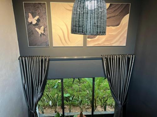 a room with a window with curtains and pictures at Nguyen Shack Retreat Resort in Phong Nha