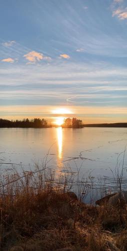 a large body of water with the sun setting at Udden in Herräng