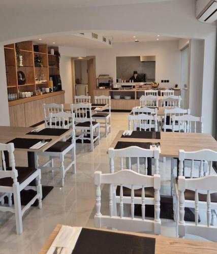 un restaurante con mesas y sillas blancas y una cocina en Soho Blue City Hotel, en Hersonissos
