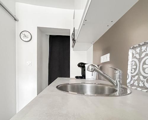 - un évier dans une cuisine avec une horloge murale dans l'établissement T2 au cœur de la vieille ville historique, à Montluçon