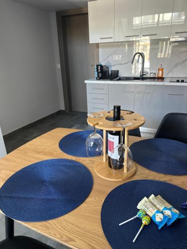 a kitchen with a wooden table with blue mats on it at Sealuxe Residence in Nea Kalikratia