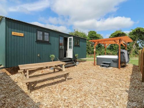 a green tiny house with a bench and a gazebo at Luxury Shepherd Hut with Private Hot Tub in Swaffham Bulbeck