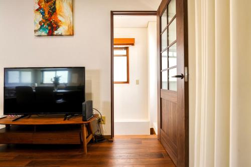 a living room with a television on a table and a door at Three minutes walk to subway Direct to the airport Umeda business district in Osaka
