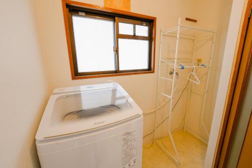 a washer and dryer in a bathroom with a window at Three minutes walk to subway Direct to the airport Umeda business district in Osaka