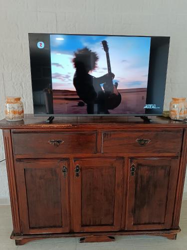 a tv on top of a wooden dresser with a guitar at Don Pablo in Luján