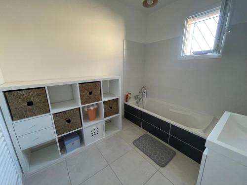 une salle de bain blanche avec une baignoire et un lavabo dans l'établissement Maison cosy au calme, à Tullins